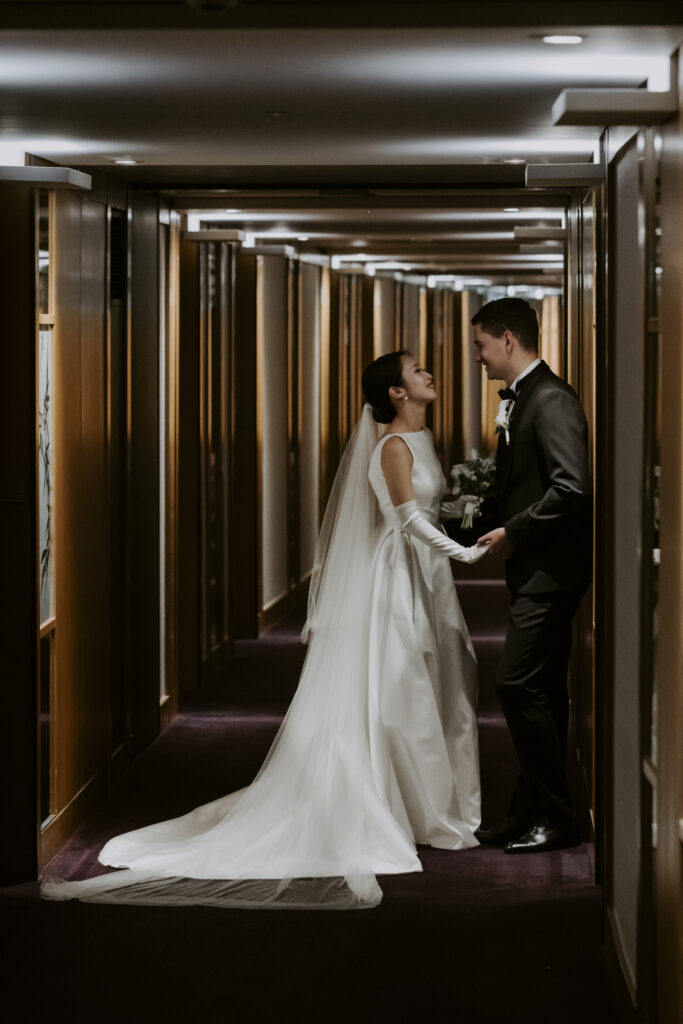 A bride and groom standing in the hallway of a hotel.