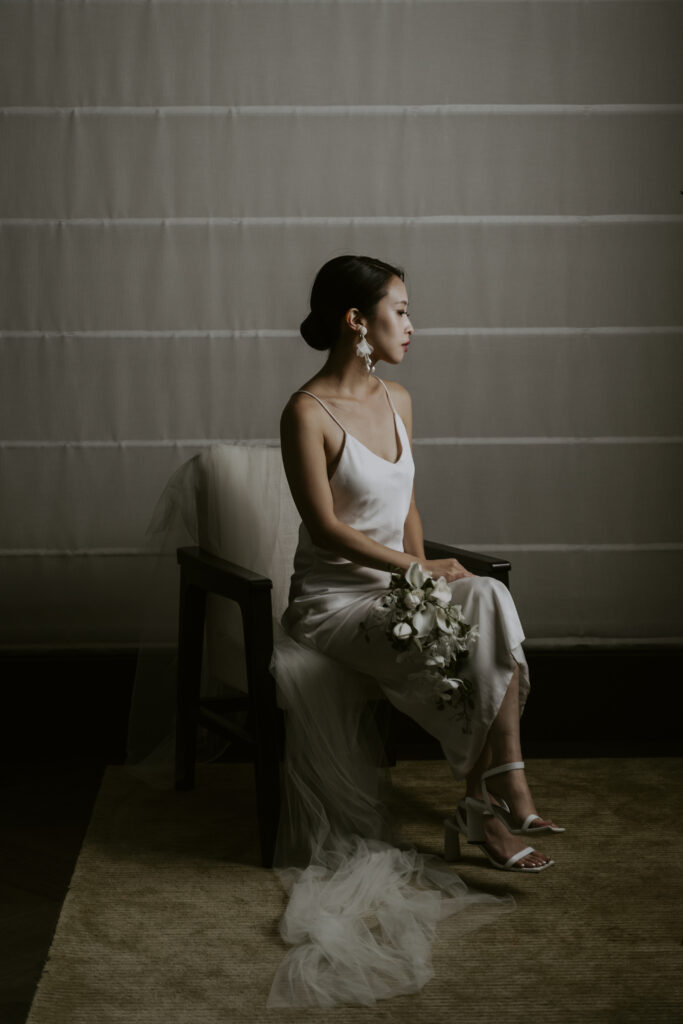 A bride sitting in a chair with her bouquet.