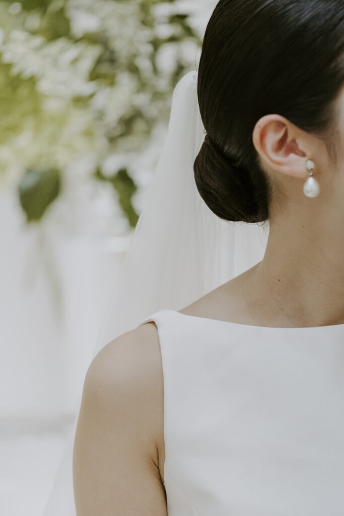 A bride wearing a white wedding dress and pearl earrings.