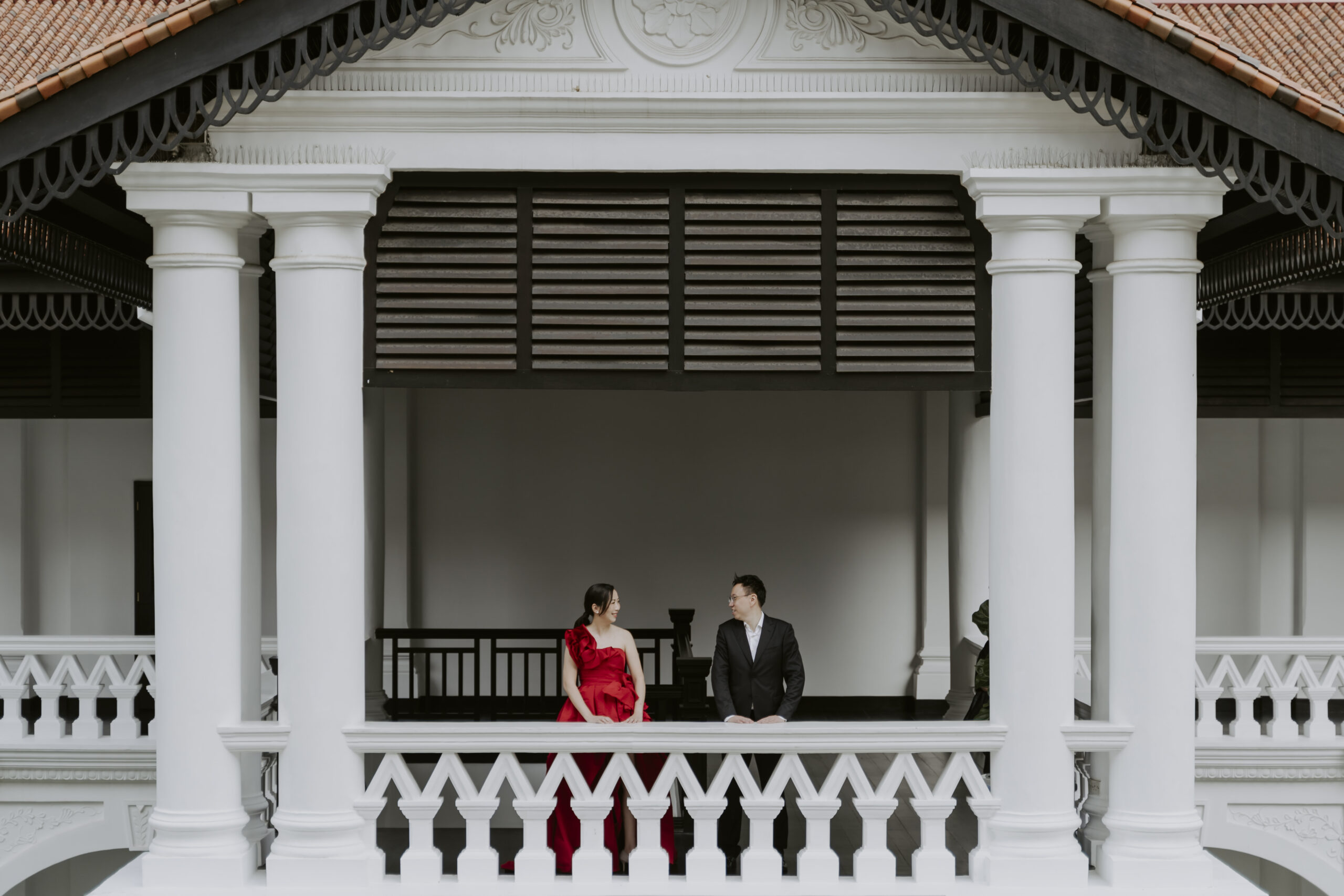 A couple in a red dress standing on the balcony of the Raffles Hotel in Singapore