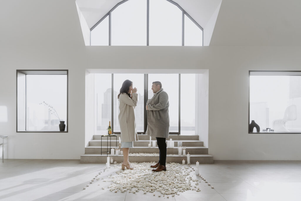 A man and woman standing in a white room.