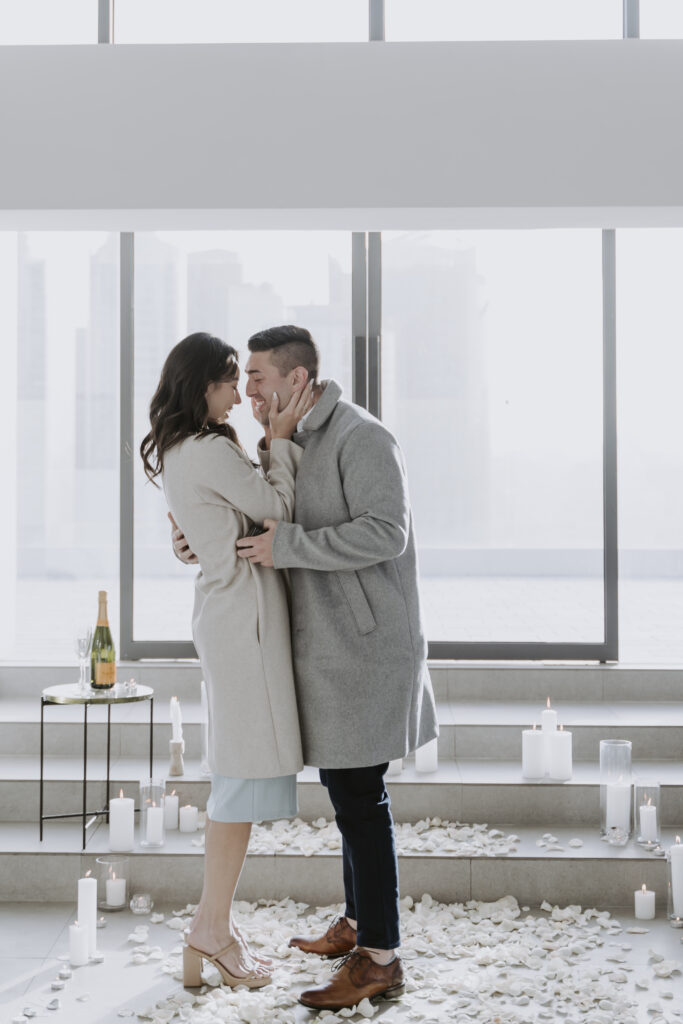 A couple embracing in front of a large window.