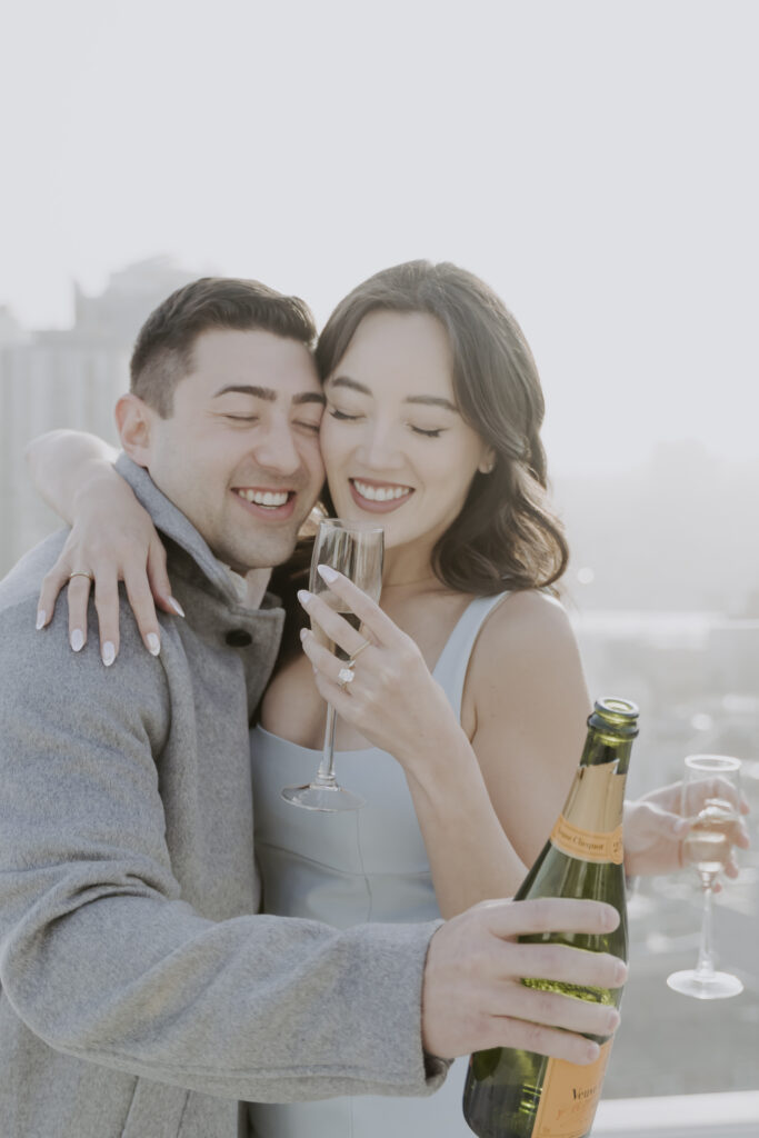 A man and woman holding champagne glasses on a rooftop.