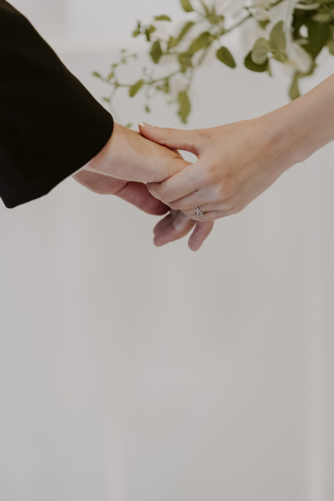 A bride and groom holding hands in front of a white background.