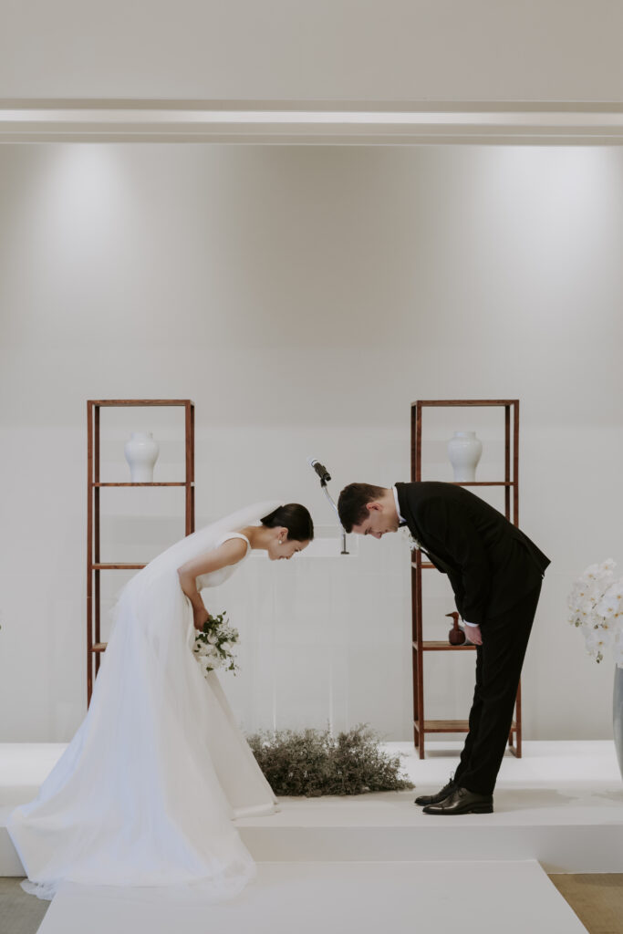 A bride and groom bowing at each other at the Seoul Grand Hyatt Hotel.