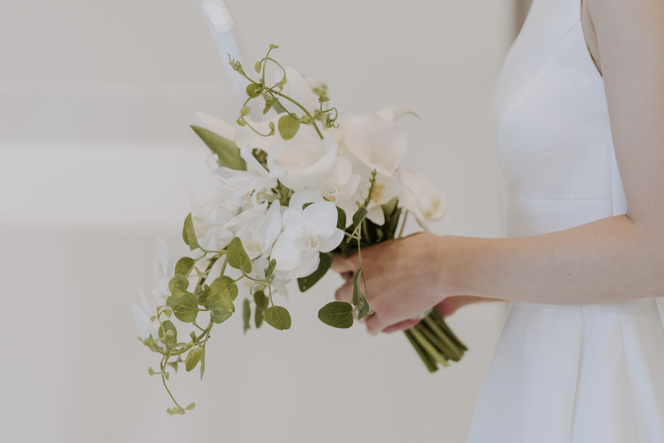 A bride in a white dress holding a bouquet of white flowers.