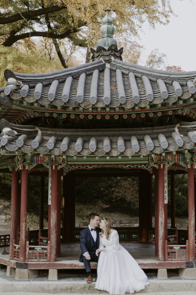 An SEOUL ELOPEMENT couple pose in front of an Asian pagoda.