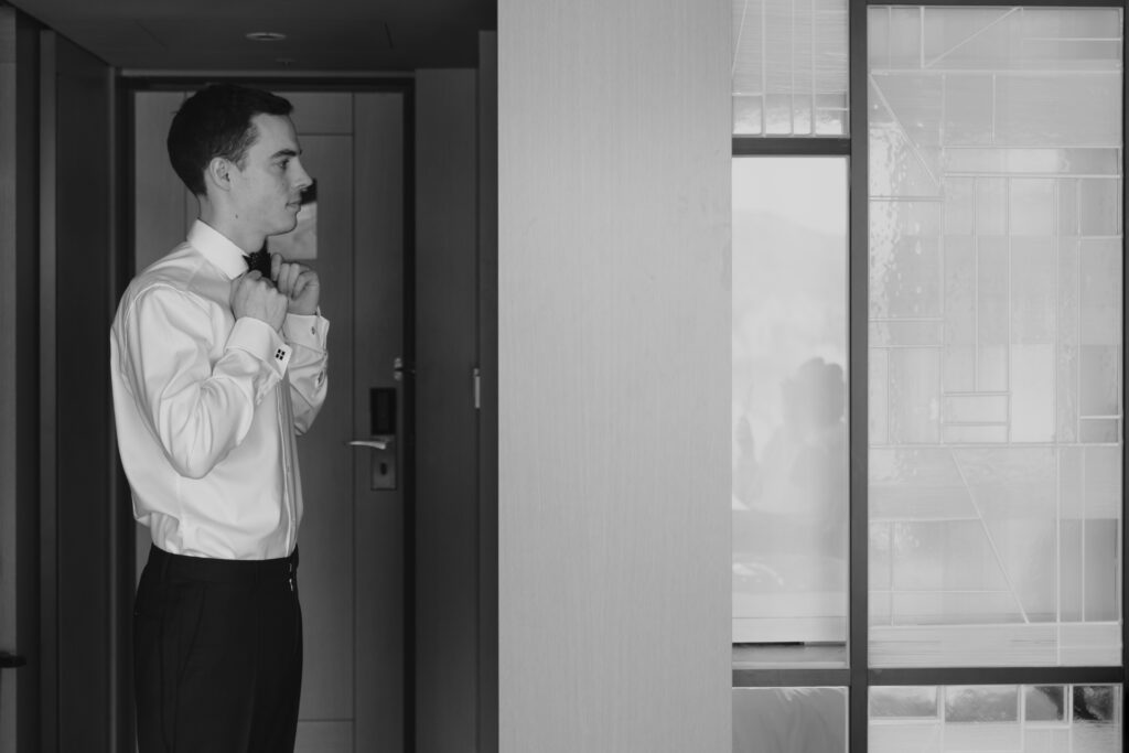 Black and white photo of a man putting on his tie in Seoul.