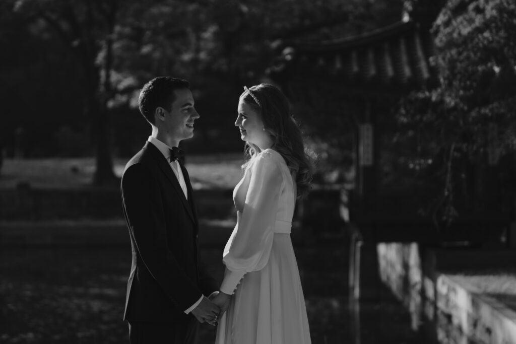 A black and white photo of a bride and groom in front of a pagoda during their Seoul elopement.