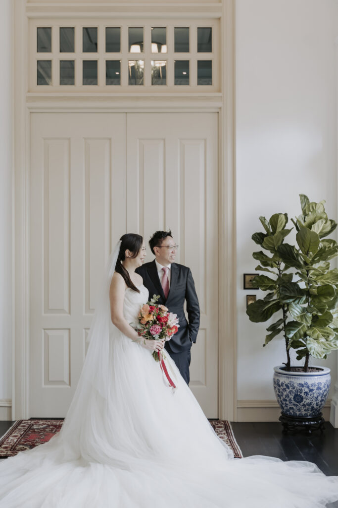 A couple in wedding attire pose at the iconic Raffles Hotel Singapore.
