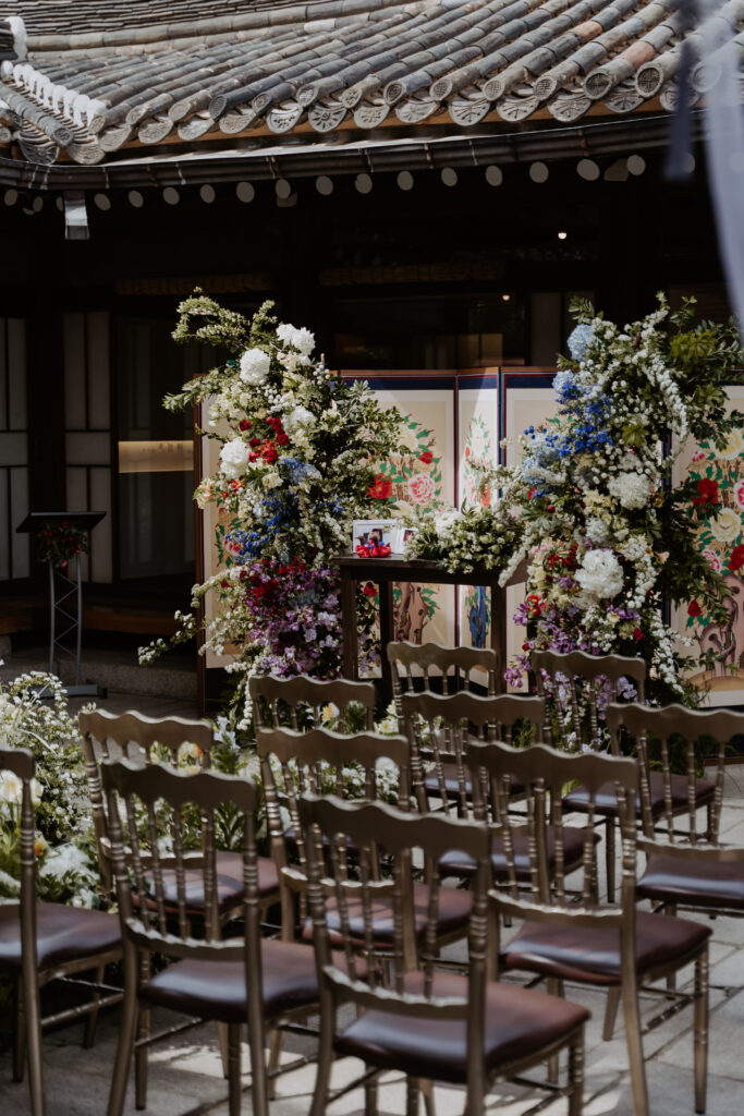 A wedding ceremony set up with chairs and flowers in a hanok house.