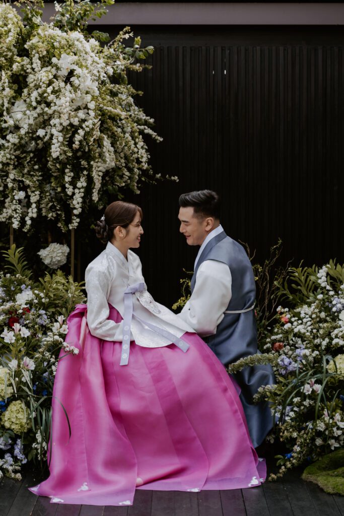 A couple in a traditional korean habok sitting in a hanok house wedding venue in Seoul.