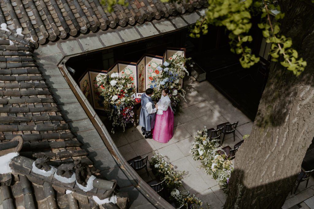 A bride and groom standing at the altar of their traditional korean wedding.