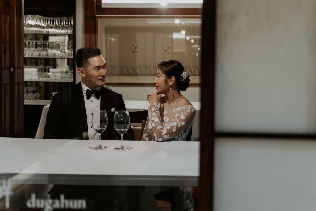 A bride and groom drink wine at their reception in Seoul.