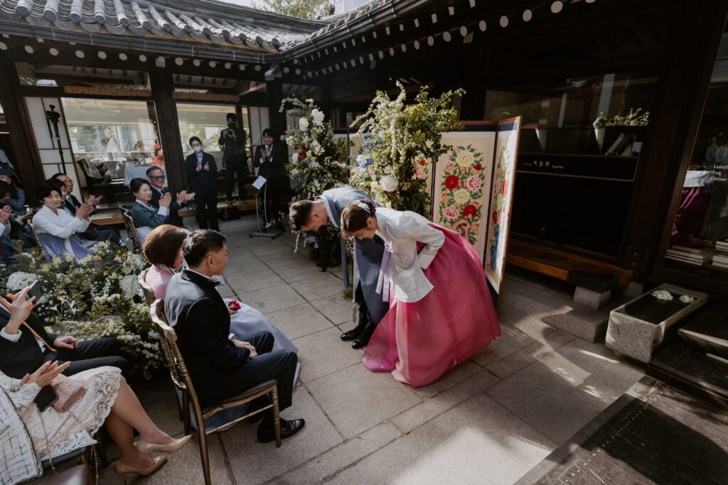 a couple dressing in traditional hanbok bow to their parents at their wedding ceremony in Seoul