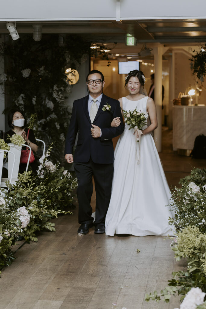 A bride and her father walking down the aisle at a korean wedding.