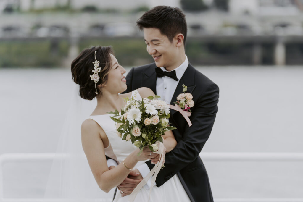 A bride and groom posing for a photo on a boat.