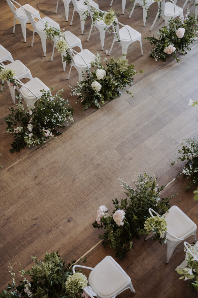 A wedding ceremony set up with white chairs and greenery in south korea.