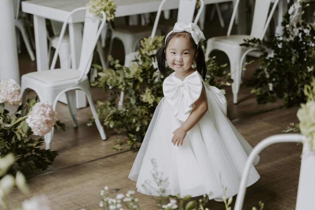 A little Korean flower girl walks down the aisle at the wedding.