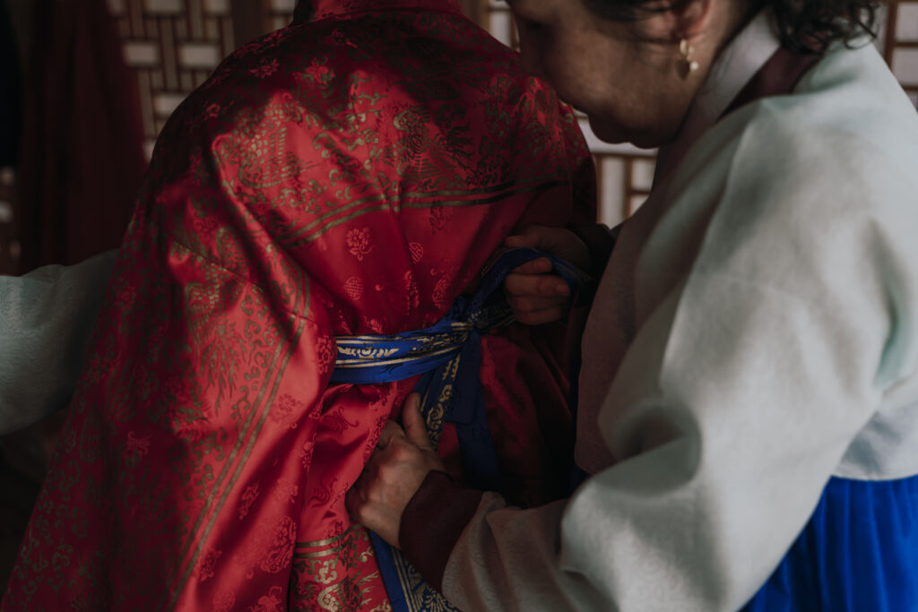 helper adjusting the bride's hanbok