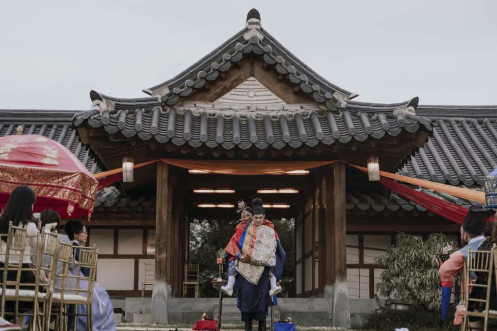 A Korean traditional wedding ceremony with a bride piggyback ride in groom while walking down the aisle.