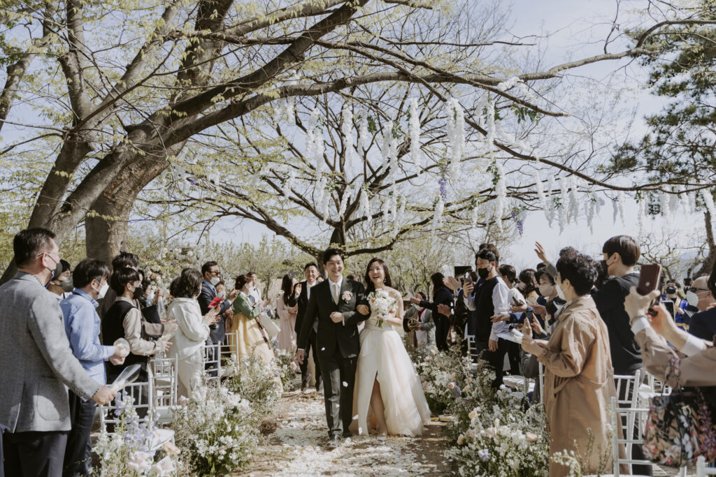 A bride and groom walking down the aisle at an outdoor wedding in south korea