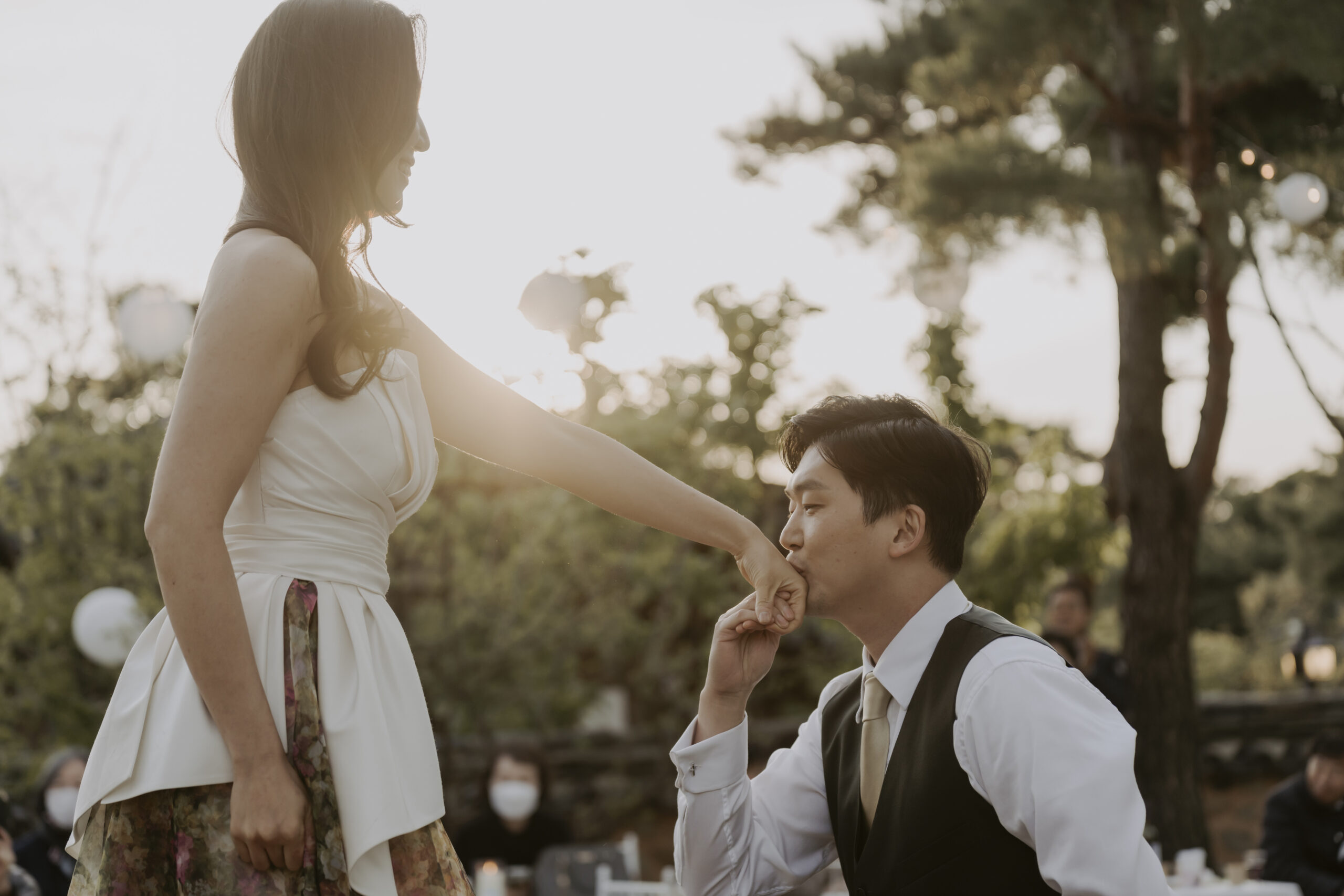 A man is holding a woman's hand in front of a table in south korea, something they included when planning their wedding in Korea.