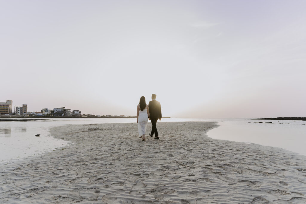 A bride and groom walking on the beach at sunset for their pre-wedding