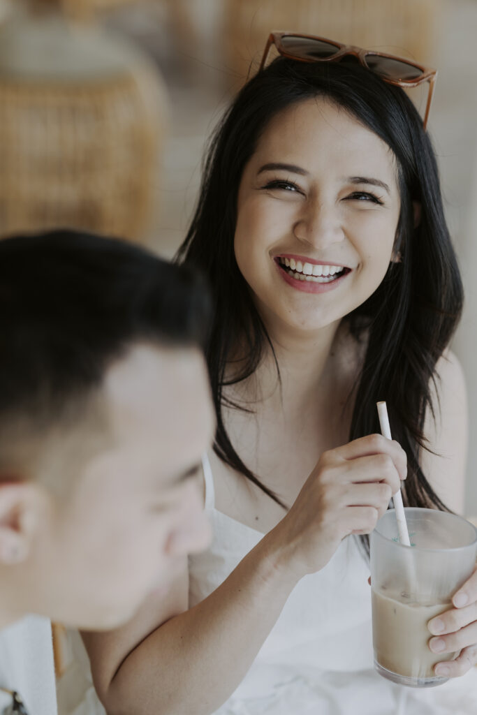 A man and woman smiling at each other while holding a cup of coffee.