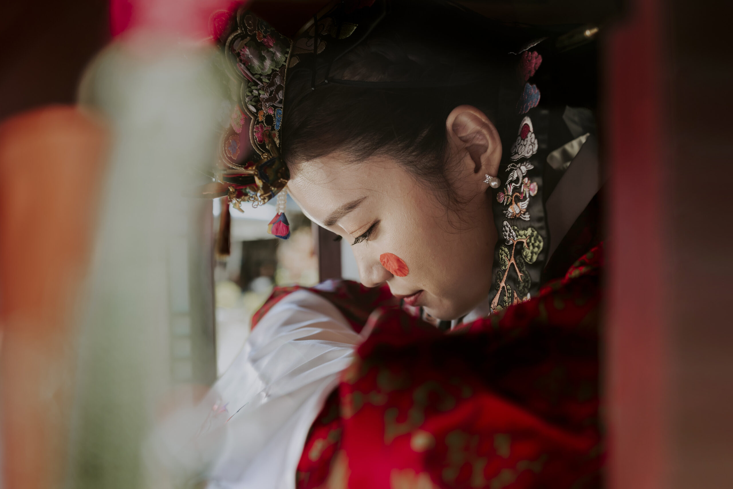 A woman in a traditional Asian dress is looking out of a window, showcasing elements of traditional attire.