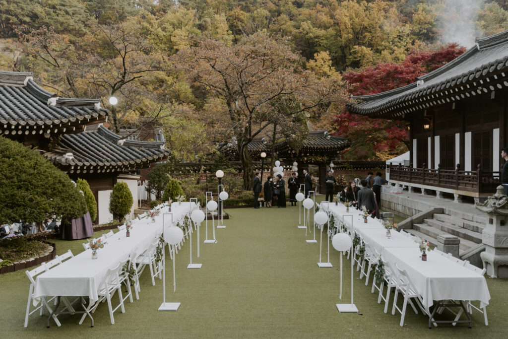 A korean wedding in a garden with tables and chairs.