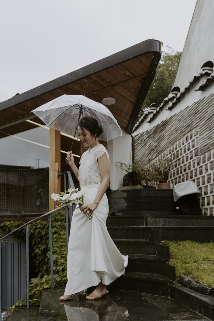 A bride with an umbrella walking down the steps of the hanok wedding venue in Bukchon, Seoul.