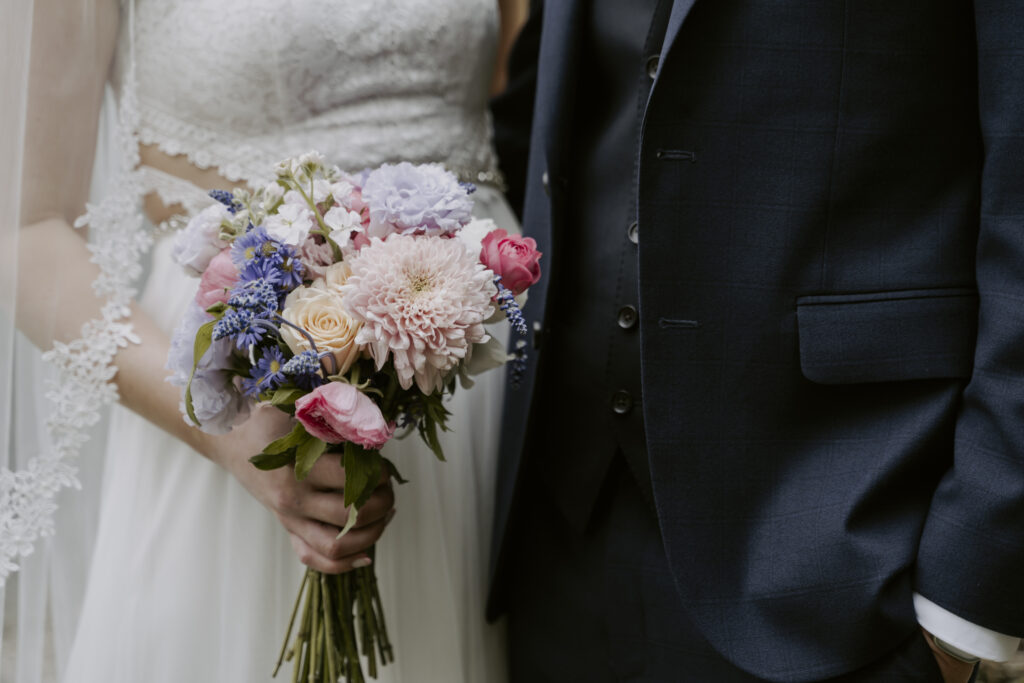 A bride and groom holding a bouquet of flowers.