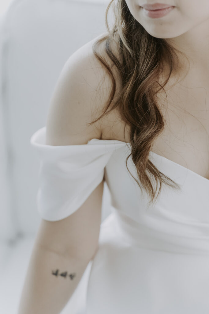 A bride in a white dress with tattoos.