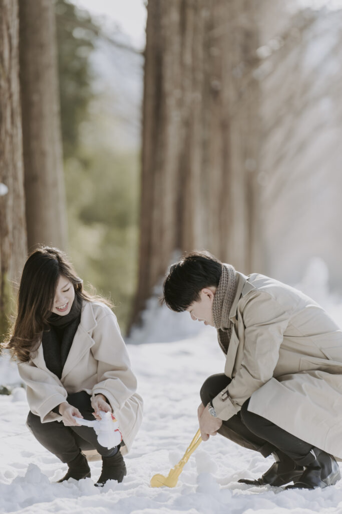 A man and woman are playing in the winter snow in Korea.
