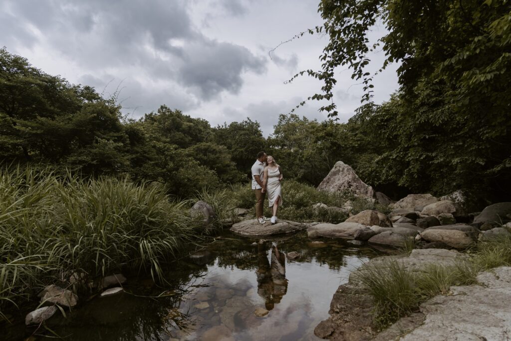 A couple standing on a rock in a pond in Damyang