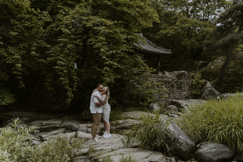 A couple embraces and kisses in a wooded area for their Damyang pre-wedding photoshoot.