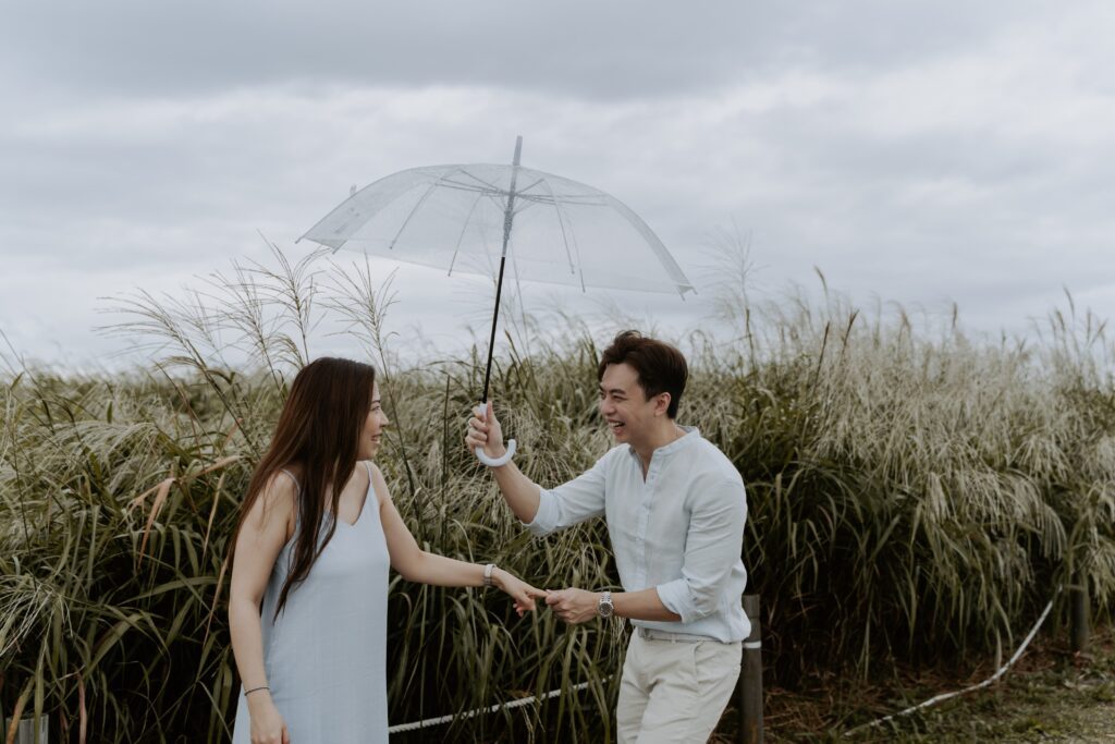 A man and woman holding an umbrella in a field.