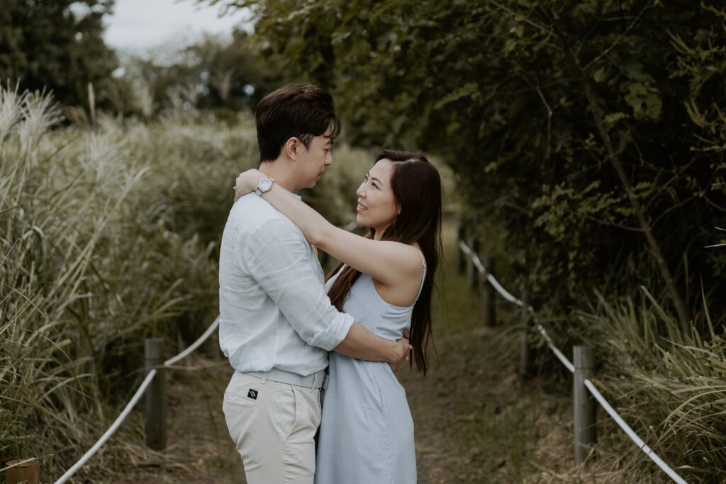 An asian couple embracing in a field of tall grass.
