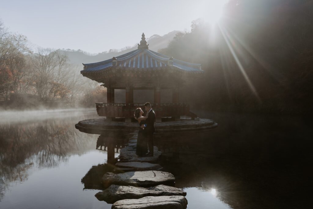 A couple standing on a stone bridge in front of a pagoda in South Korea.