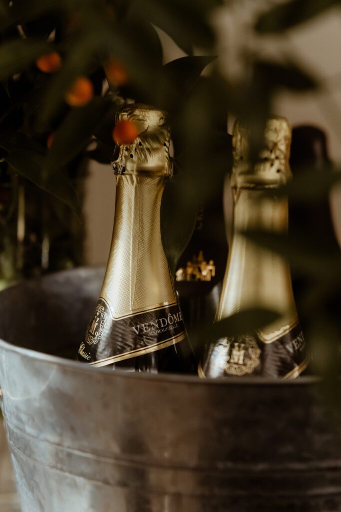Two champagne bottles in a metal ice bucket, partly obscured by plant leaves in the foreground, set the scene for an elegant Korean wedding.