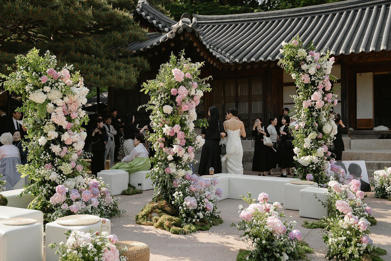 Outdoor wedding ceremony with floral arches and guests seated before a traditional Korean building—one of the most picturesque wedding venues in Korea.